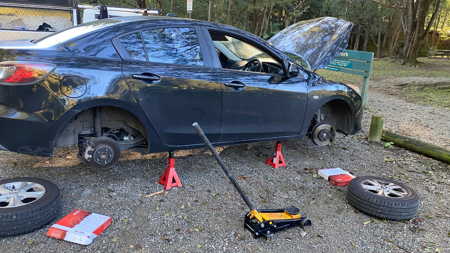 Car up on axle stands with both wheels off during a mobile brake repair on the Gold Coast